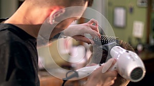 Professional tattooed barber giving a new haircut to his client in a barbershop