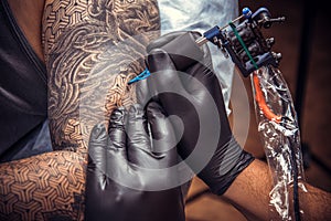 Professional tattooer showing process of making a tattoo in tattoo studio