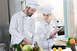 Professional team of cooks checking recipe during