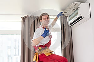 Professional technician maintaining modern air conditioner indoors.