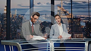 Professional television presenters talk evening newscast modern studio closeup