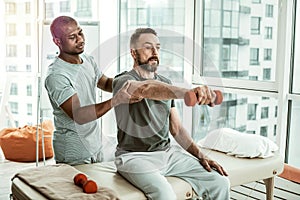 Professional therapist helping his client to do exercise