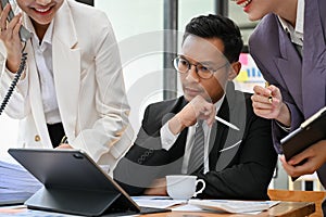 Thoughtful adult Asian businessman planning his business project with his team