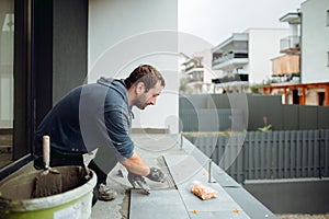 Professional tiler placing tiles in position with levelling system and level ceramic tiles