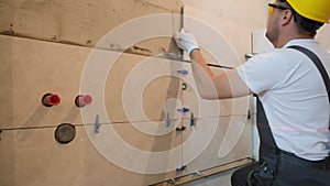 A professional tiler works in the bathroom of a modern house. A man lays tiles.