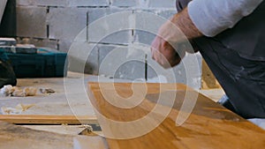Professional tiling carpenter measures and marking a wooden plank at construction site