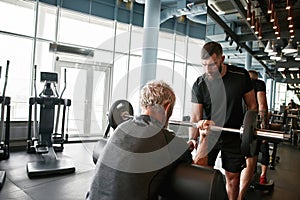 Professional trainer carefully choosing workout activities for aged man