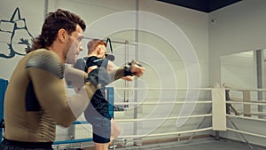 Professional training of two young fighters making dynamic exercises in front of the mirror on ringside, side view.