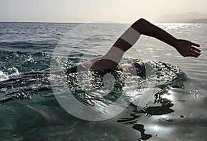 Professional triathlete practicing in open water. Swimming in se