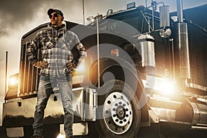 Professional Truck Driver Proudly Standing in Front of His Heavy Duty Vehicle