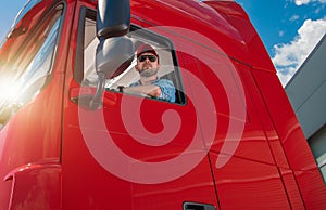 Professional Trucker Behind the Semi Tractor Truck Wheel