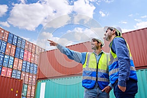 Professional of two Engineers or foreman container cargo wearing white hardhat and safety vests checking stock into container for