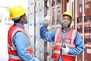 Professional of two Engineers or foreman container cargo wearing yellow hardhat and safety vests checking stock into container for