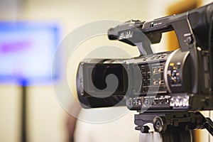 Professional video camera mounted on a tripod to record video during a press conference, an event, a meeting of journalists.