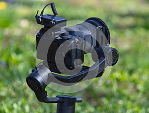 Professional video camera on tripod in green grass. Shallow depth of field