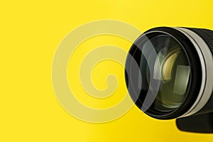 Professional video camera on yellow background, closeup. Space for text