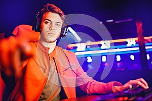 Professional video gamer playing online games tournaments pc computer with headphones, Blurred red and blue background