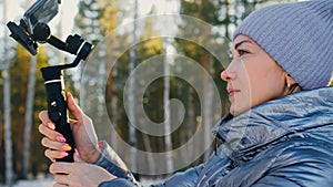 Professional Videographer Holding DSLR Camera on 3-axis Gimbal Stabilization Device in Winter. Cinematographer Operator