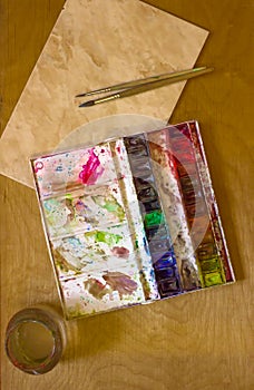 Professional watercolor aquarell paints in box with brushes on old wooden board
