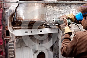 Professional welder in autovehicle factory working on the body