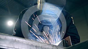 Professional welder in a helmet and sparks caused by welding