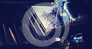 Professional welder performs welding work on metal in protective mask. Industrial worker concept