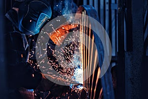 Professional welder performs welding work on metal in protective mask. Industrial worker concept