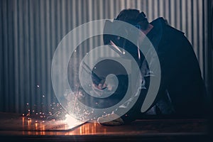 Professional welder performs welding work on metal in protective mask. Industrial worker concept