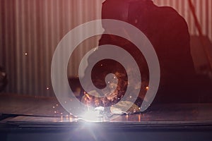 Professional welder performs welding work on metal in protective mask. Industrial worker concept