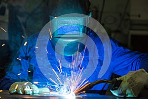Professional welder welding metal pieces in steel construction photo