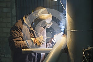 A professional welder welds a pipe with a diameter of DN100 for a process pipeline to an oil refinery in Russia