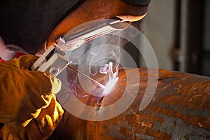 A professional welder welds a pipe with a diameter of DN250 for a process pipeline and corrects defective sections of the seam for