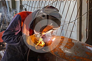 A professional welder welds a pipe with a diameter of DN250 for a process pipeline and corrects defective sections of the seam for