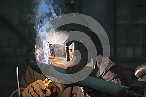 A professional welder welds a pipe with a diameter of DN50 for a process pipeline to an oil refinery in Russia