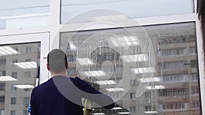 A professional window cleaner soaps and squeegies a window clean, male cleaning worker.