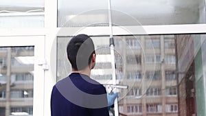 a professional window cleaner soaps and squeegies a window clean, male cleaning worker.
