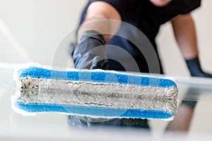 Professional window cleaner using a window cleaning washer sleeve to cleanse a large fold down apartment window