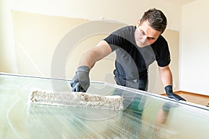 Professional window cleaner using a window cleaning washer sleeve to cleanse a large fold down apartment window