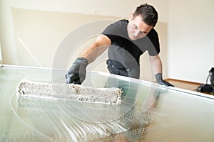 Professional window cleaner using a window cleaning washer sleeve to cleanse a large fold down apartment window