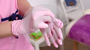 Professional woman beautician puts on her hands blue rubber clean sterile gloves before doing the procedure for cosmetic