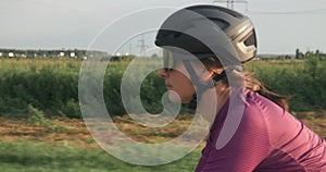 Professional woman cyclist is cycling on bicycle at sunset. Female triathlete is training on road bike and preparing for triathlon