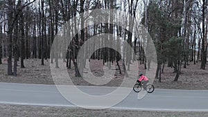 Professional woman cyclist is riding and training on road bike alone. Female athlete pedals intensively on bicycle on empty car ro