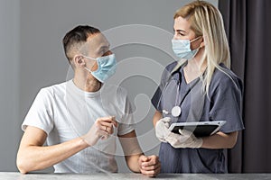 Professional woman doctor with a stethoscope is using a computer tablet standing together with her patient