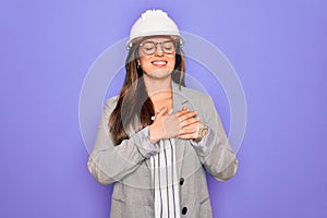 Professional woman engineer wearing industrial safety helmet over pruple background smiling with hands on chest with closed eyes