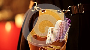 Professional woman hairdresser barber hand in glove taking out scissors shears out of little thigh comb bag in close up