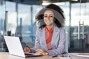 Professional woman with headset working at laptop in office