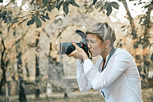 Professional woman photographer taking camera outdoor portraits with prime lens in the photography nature. Greenery tone