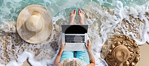 Professional woman using laptop on sandy beach at tropical resort during summer holiday