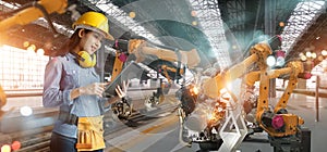 Professional women engineer check and control welding robotics automatic arms machine in intelligent factory automotive industrial