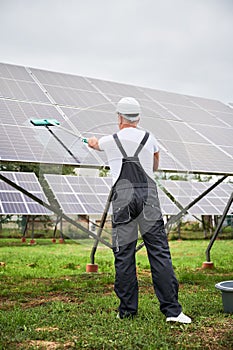 Professional worker cleaning solar PV panel.